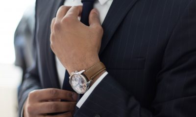 A person in formal attire, adjusting their tie