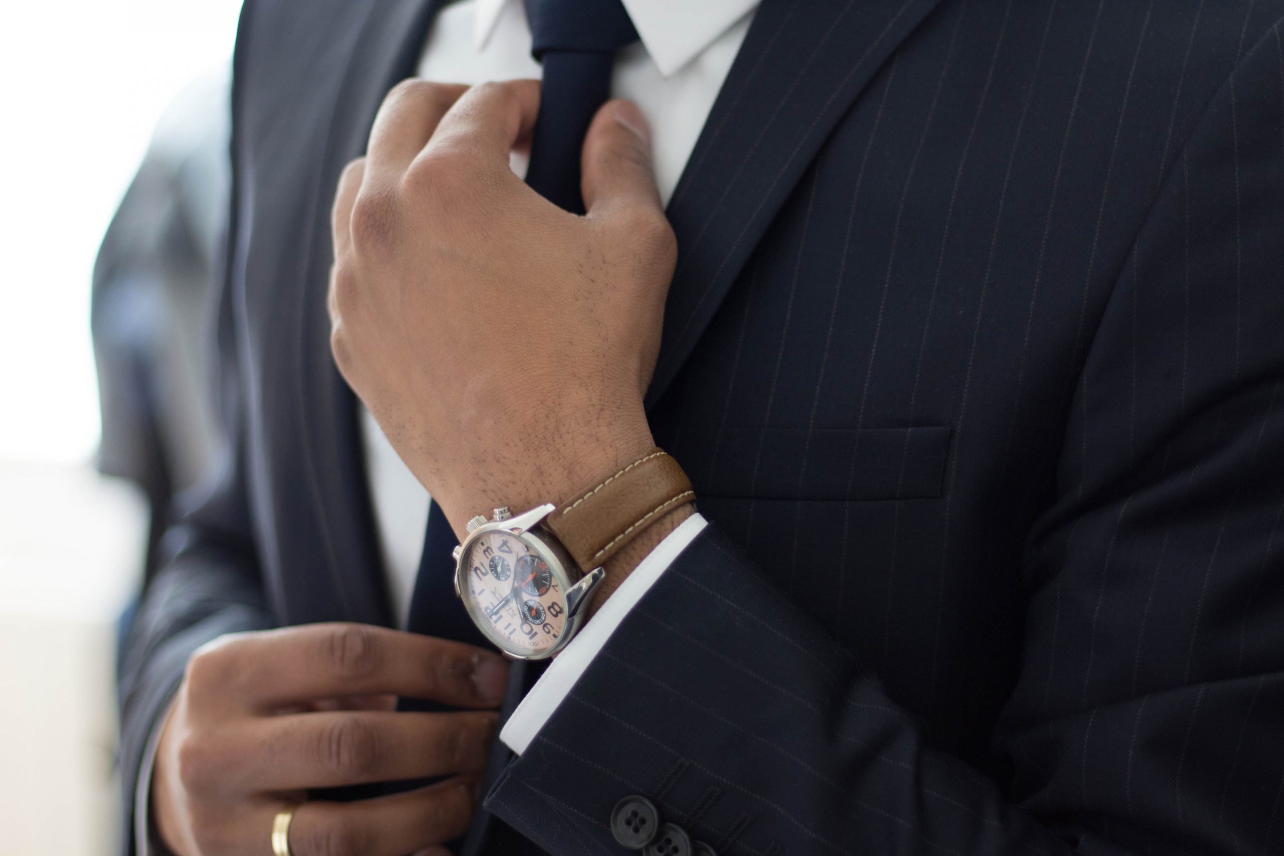 A person in formal attire, adjusting their tie